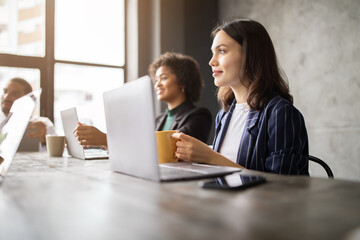 Leinwandbilder - A diverse group of professionals is engaged in a meeting at a contemporary office space. They are sharing ideas while working on laptops and enjoying beverages, fostering collaboration and creativity.