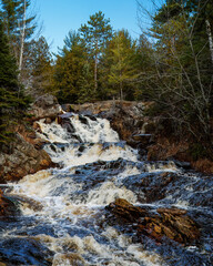 Wall Mural - A cascading waterfall in the wilderness on a sunny blue sky day.