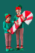 © Pixel-Shot - Shocked little children in elves costumes with candy cane pinata on green background