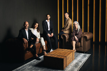 Fototapete - A group of European business professionals is gathered indoors, engaged in discussion. The modern office features stylish leather seating and warm lighting, creating a professional ambiance.