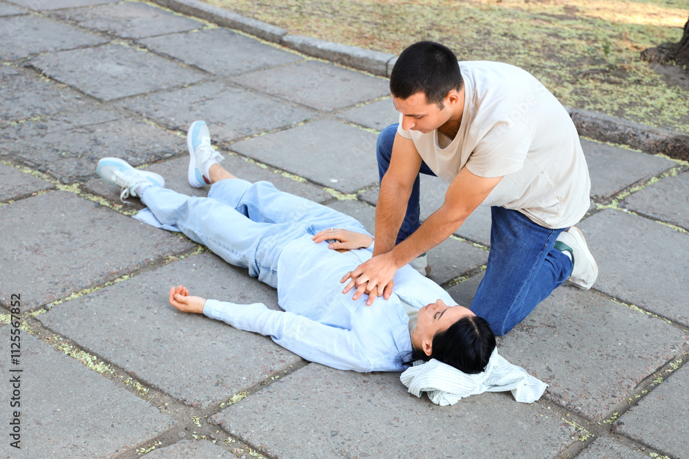 Young man doing CPR on unconscious wife having heart attack in park