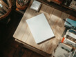 © Andri - A top-down view of a white magazine lying on a wooden table in a small store. magazine and book mockup
