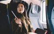 © BullRun - Pensive asian female author thinking about article creation holding pen and notepad sitting in wagon, young woman student looking away pondering on ideas and plannings spending time on trip in train