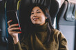 © BullRun - Positive asian female sitting in comfortable seat of locomotif traveling and using smartphone for chatting and checking social networks,smiling woman traveler enjoying wireless connection in train