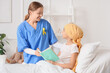 © Pixel-Shot - Little girl after chemotherapy with nurse reading book in bed at hospital. Childhood cancer awareness concept