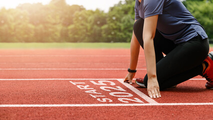 starting to the new year 2025. woman preparing to start on an athletics track engraved with the year