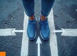 © hakule - A person standing at an intersection, facing two different directions with white arrows pointing in each direction on the asphalt floor.