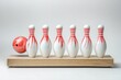 © khalid_spk - A red bowling ball knocking over a group of white bowling pins with red stripes