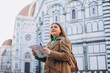 © mdyn - Happy 30s young woman with map in old town in Florence. Holidays and tourism concept. Female tourist searching direction on location map outdoors. Stylish woman visiting Italian landmarks