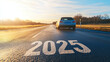 © Ruslan - Number 2025 on asphalt of highway on which car is driving. New year travel concept