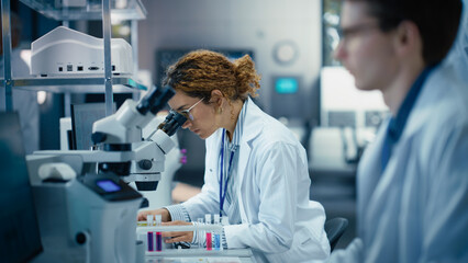 Aufkleber - Medical Research and Development Laboratory: Beautiful Hispanic Female Scientist Working on a Computer and Looking at a Sample in a Petri Dish Under a Microscope. Advanced Biotechnology Lab