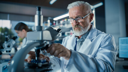 Aufkleber - Senior Medical Research Scientist Looking at Biological Samples Under a Microscope in an Applied Science Laboratory. Portrait of a Handsome Middle Aged Doctor Working on a Research Project