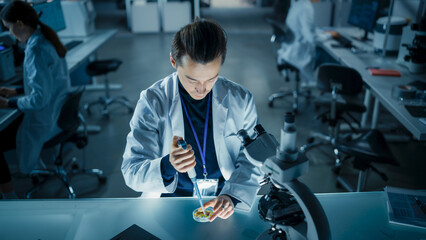 Aufkleber - Biology Research Scientist Applying a Molecular Sample with a Micro Pipette and Researching Under a Microscope in a Science Laboratory. Young Lab Engineer in White Coat Working on Vaccine Products
