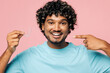 © ViDi Studio - Young smiling Indian man he wear blue t-shirt casual clothes hold in hand point on invisible transparent aligners, invisalign dental braces isolated on plain pastel pink background. Lifestyle concept.