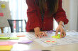 © Prathankarnpap - Young designer arranging sticky notes and app prototypes during a user experience UX design session