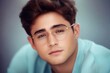© wernerimages - A gentle portrait shows a young man reflecting with his soft eyes and light beard, wearing glasses, suggesting a contemplative mood in a serene setting.