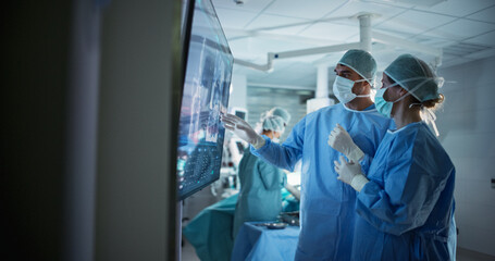 Aufkleber - Caucasian Male and Female Surgeons Analyze Scans on a Digital Monitor, Planning Surgical Strategy in a High-tech Operating Room. Colleagues Working Together, Preparing for Surgery
