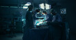 © Gorodenkoff - Dark Operating Room with a Diverse Team, Including a Black Male Assistant and a White Female Surgeon, Perform a Precise Surgical Procedure as Teamwork and Under Surgical Light