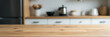 © fotoluigi868 - A wood table top is positioned somewhat obscuring part of a blurred kitchen background with surrounding countertop visible._00002_