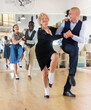 © caftor - Senior woman and younger man dancing swing in studio