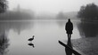 © Grzegorz Kuczynski - Silhouette of a man standing by a foggy lake with a bird nearby, evoking solitude and calm.