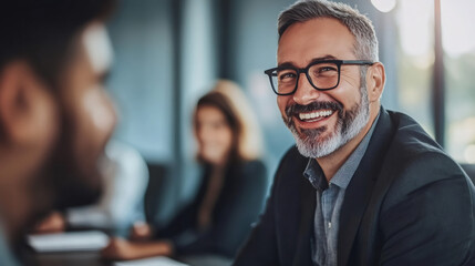 Canvas Print - Photo of a cheerful businessman in glasses conversing with coworkers at a contemporary office meeting