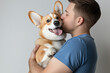 © Tondone - A joyful moment captured between a man and his corgi. The affectionate bond is evident as the man kisses his happy dog, showcasing love, companionship, and pet ownership.