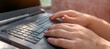 © Zhanna - A man works on a laptop outdoors, hands on a keyboard closeup.