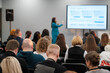 © Anton Gvozdikov - Audience engaged during a presentation with speaker using a microphone and a screen.