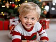 © VISUAL BACKGROUND - A little boy laying on the floor with a present in front of a Christmas tree