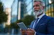 © aciddreamStudio - Businessman using a tablet in front of a modern office building
