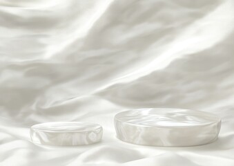 Aufkleber - Two smooth, round white objects resting on a softly draped white fabric.