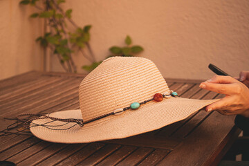 person looking at cell phone while holding a pamela style hat with colorful beads