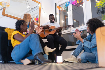 Friends clapping and having fun at home party with guitar music