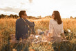 © kieferpix - Romantic date. Beautiful couple is enjoying picnic time at sunset talking enjoying nature together