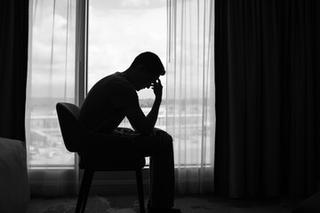 sad man in a dark room full of desperation thoughts. portrait of thoughtful sad man alone. fear, sad