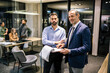 © Mediteraneo - Two businessman finishing paperwork in their office during a meeting.