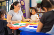 © Carlostock - Primary school teacher guiding boys and girls in classwork, all individuals are Colombian Latinos