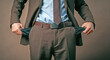 © TAMER YILMAZ - A man in a suit pulls his trouser pockets to show that there is no money in both pockets. The concept of a man without money.
