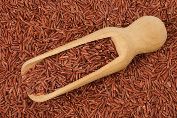 Wall Mural - red rice in a wooden scoop as a background. Top view. Flat lay