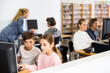 © JackF - Group of young girls and boys sitting in computer classroom of library and exercising.