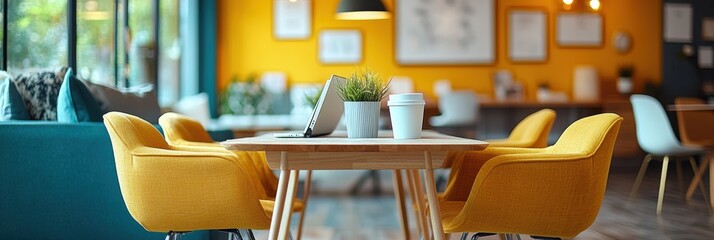 Wall Mural - A modern, brightly lit coworking space featuring vibrant yellow chairs around a wooden table with a laptop and coffee cup, fostering productivity.