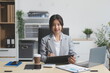 © Kansuda - Successful Asian businesswoman smiling using laptop computer and holding coffee cup at office. Confident Asia businesswoman sitting happily in the office.
