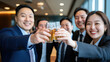 © Lerson - Celebrating success, vibrant group of Asian professionals toasting with glasses of beer in modern office setting