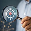 © Tekin - Hand holding a magnifier over the target icon. Focusing on a target concept.