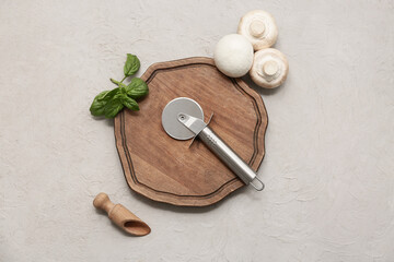 Canvas Print - Wooden board with stainless steel pizza cutter and mushrooms on light background