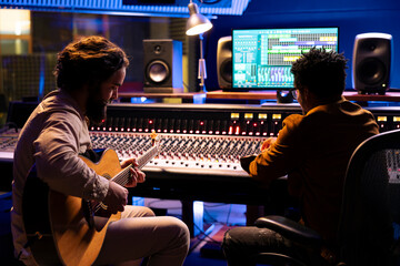 Aufkleber - Musician records electro acoustic guitar sounds with technician in studio, doing mix and master techniques to create a track. Talented artist does live performance with instrument in control room.