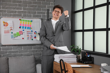 Wall Mural - Happy businessman with papers meeting deadline in office