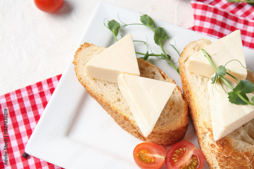 Plate with bread, triangles of tasty processed cheese, micro green and tomatoes on light table, closeup