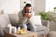 © Pixel-Shot - Ill young man drinking lemon tea on sofa at home